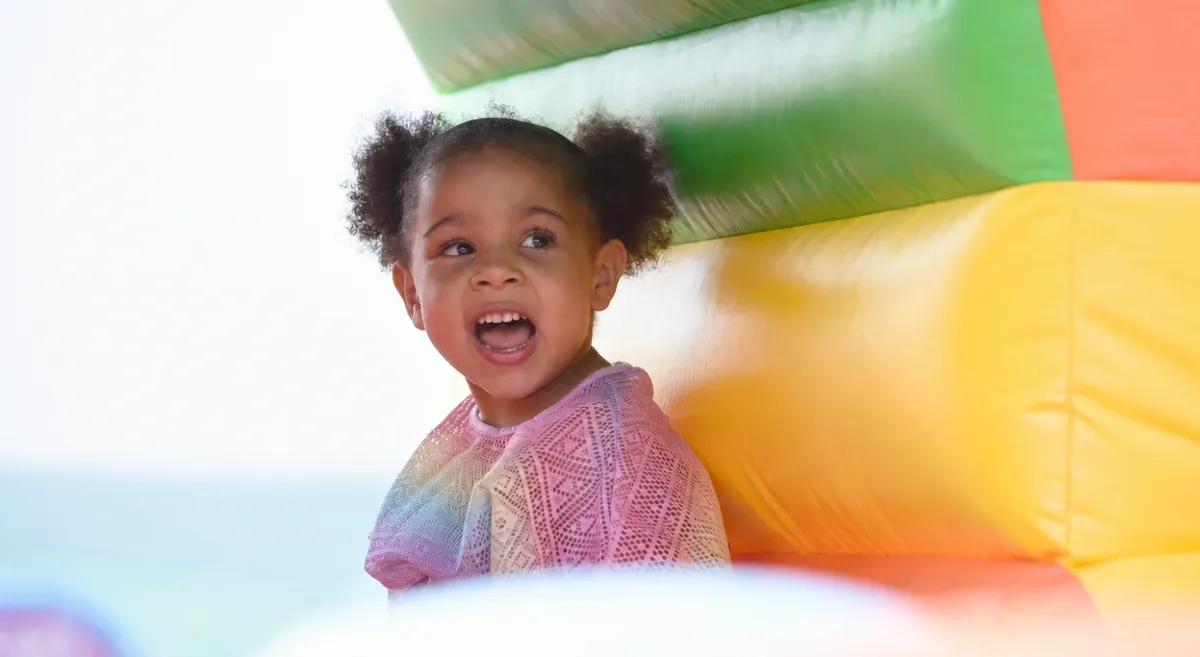 A small child laughing inside a brightly coloured inflatable play structure